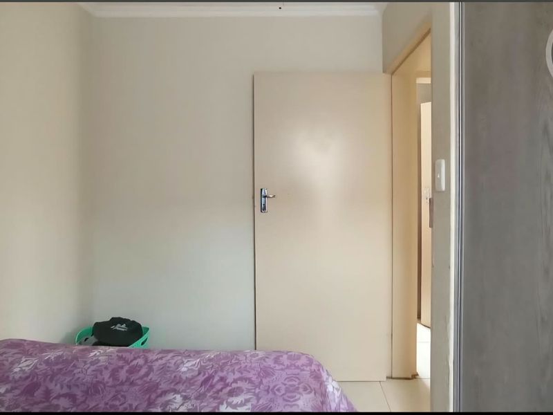 A simple bedroom featuring neutral walls and a built-in cupboard, offering a functional space ready for personalization.