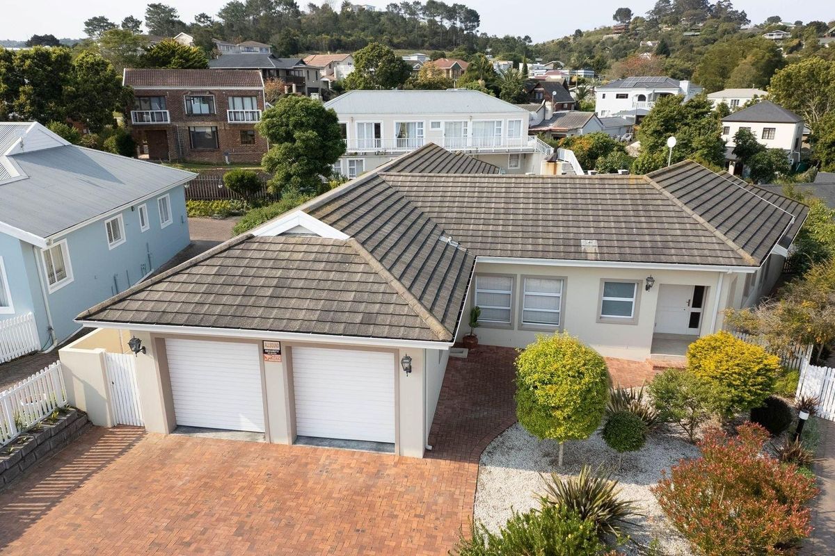 Aerial view of the property featuring a double garage, paved driveway, and tiled roof, set within a well-maintained residential neighborhood.