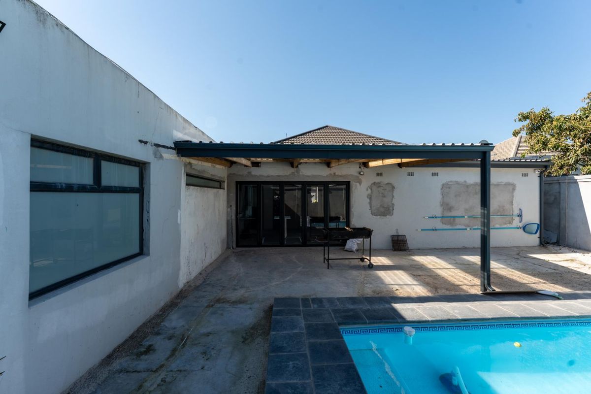 Rear exterior area featuring a swimming pool and a partially completed covered patio with aluminium stacker doors and unfinished wall surfaces.