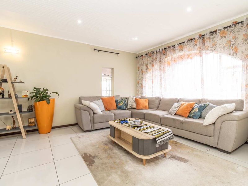 A bright and spacious living room featuring large arched windows, tiled flooring, and a classic tongue and groove ceiling with recessed lighting.