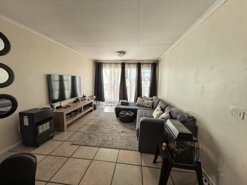 A living room featuring tiled flooring, coved cornices, and a sliding glass door providing access to an outdoor area.