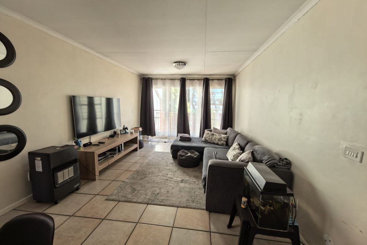A living room featuring tiled flooring, coved cornices, and a sliding glass door providing access to an outdoor area.