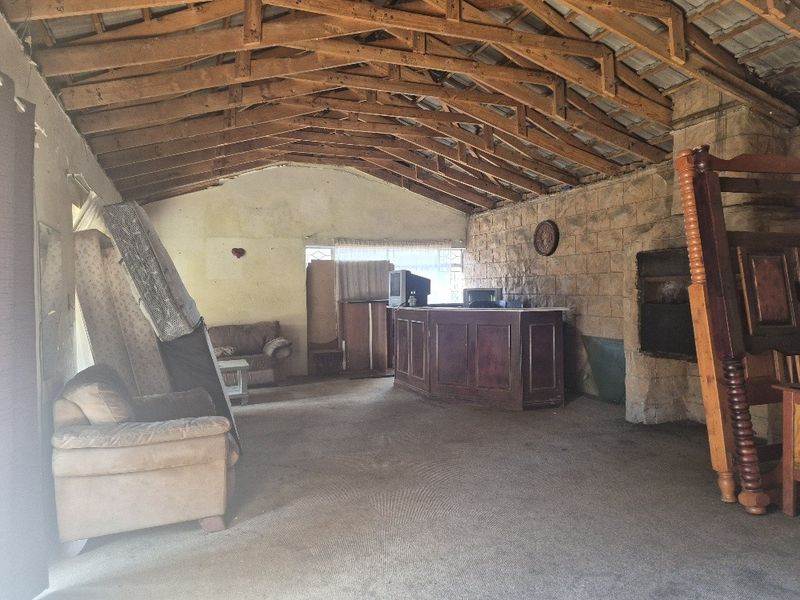 Spacious living area featuring exposed timber roof trusses, a stone feature wall with a built-in fireplace, and a built-in bar counter.