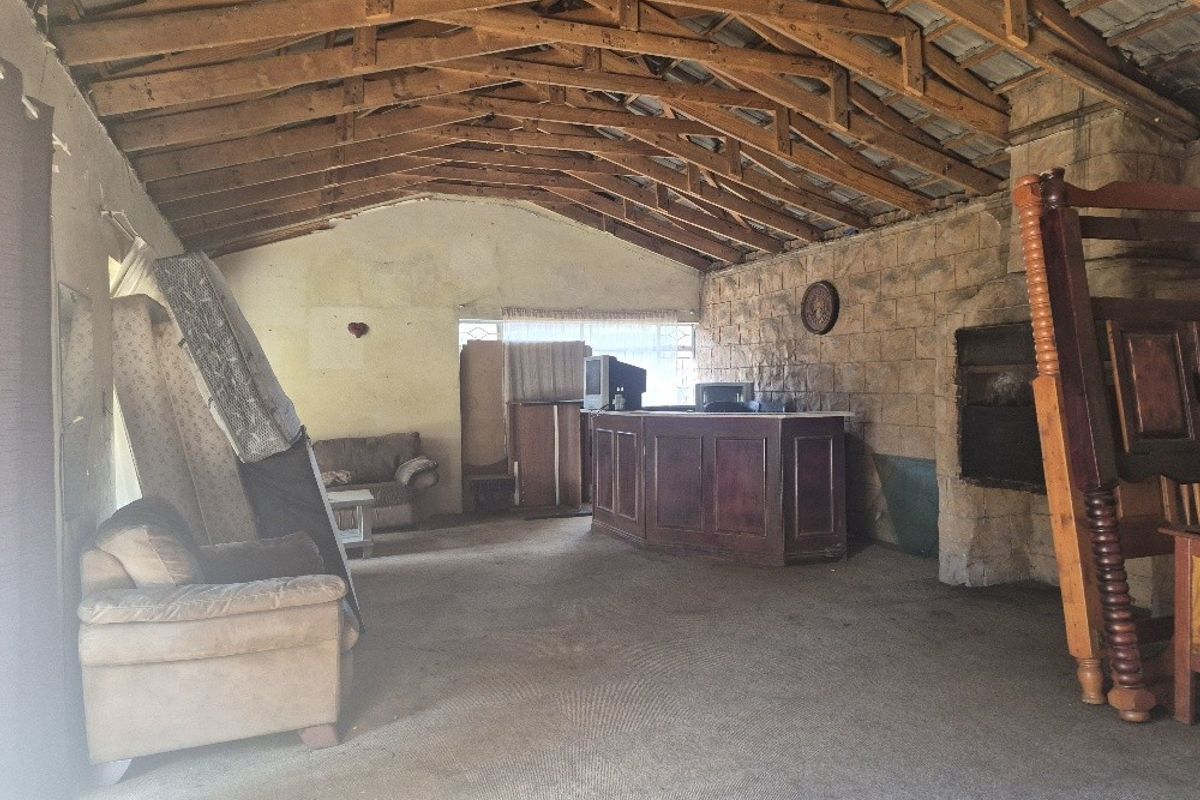 Spacious living area featuring exposed timber roof trusses, a stone feature wall with a built-in fireplace, and a built-in bar counter.