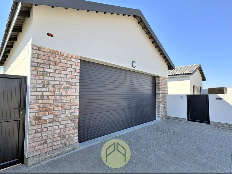A modern garage exterior featuring a dark sectional door, brick accents, and a neatly paved driveway entrance.