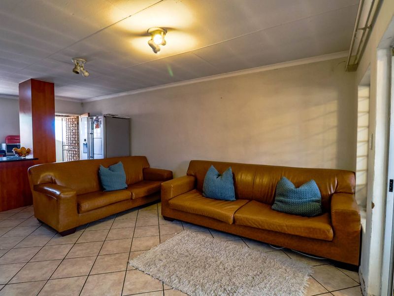 Open plan living area featuring ceramic tile flooring and an adjacent kitchen space with built-in cabinetry.