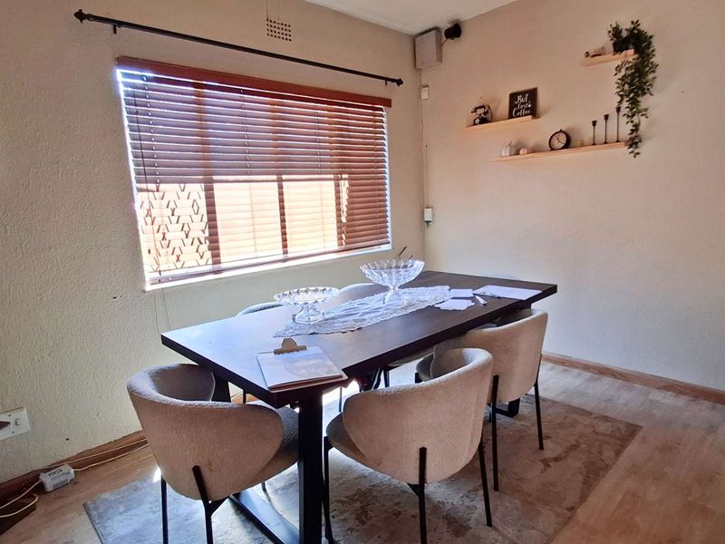 A dining room area featuring laminate flooring and venetian blinds, providing a functional space for meals.