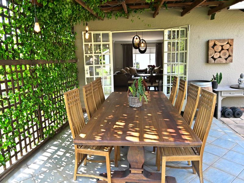 A covered outdoor patio featuring a wooden pergola, climbing greenery on a trellis, and tiled flooring, providing seamless access to the interior living space.