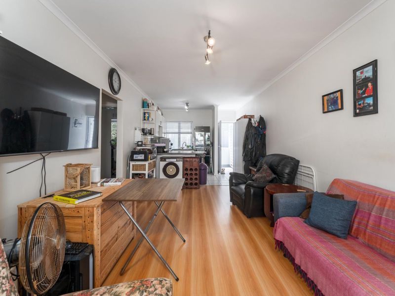 Open plan living area featuring laminate flooring and integrated kitchen space with laundry facilities, offering a functional layout for modern apartment living.