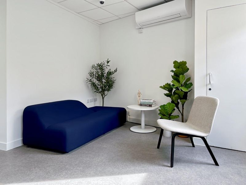 A clean, modern office space featuring a suspended ceiling, wall-mounted air conditioning unit, and durable commercial flooring.