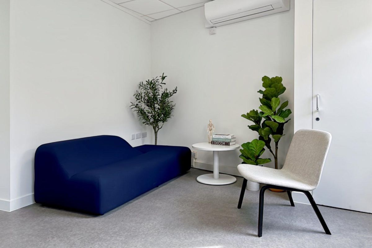 A clean, modern office space featuring a suspended ceiling, wall-mounted air conditioning unit, and durable commercial flooring.