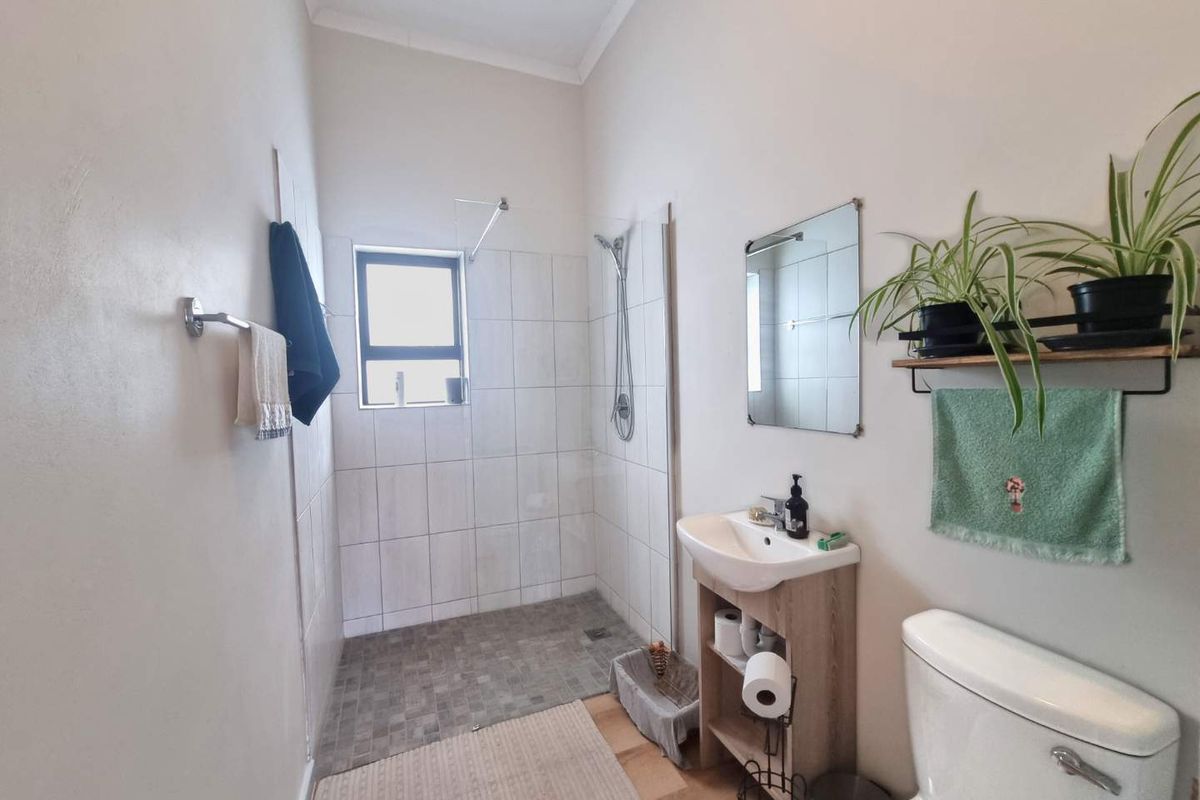 A functional bathroom featuring a walk-in shower with tiled surround, a pedestal vanity, and a standard toilet.