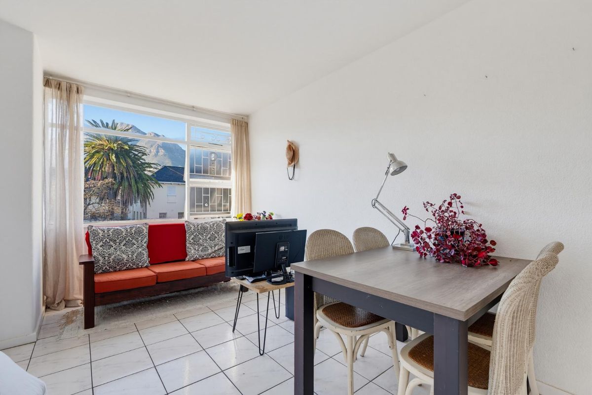 A bright living area featuring large windows with mountain views and tiled flooring, offering a functional space with natural light.