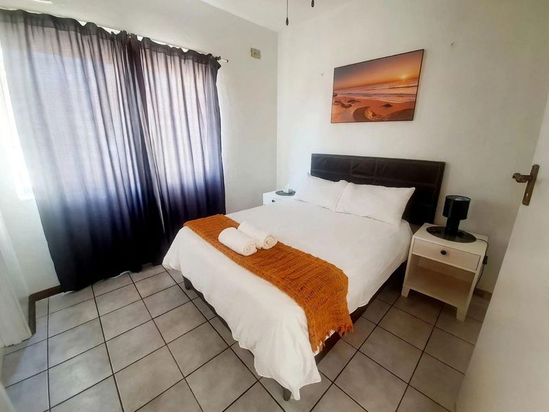 A functional bedroom featuring tiled flooring and a ceiling fan, providing a comfortable and practical living space.