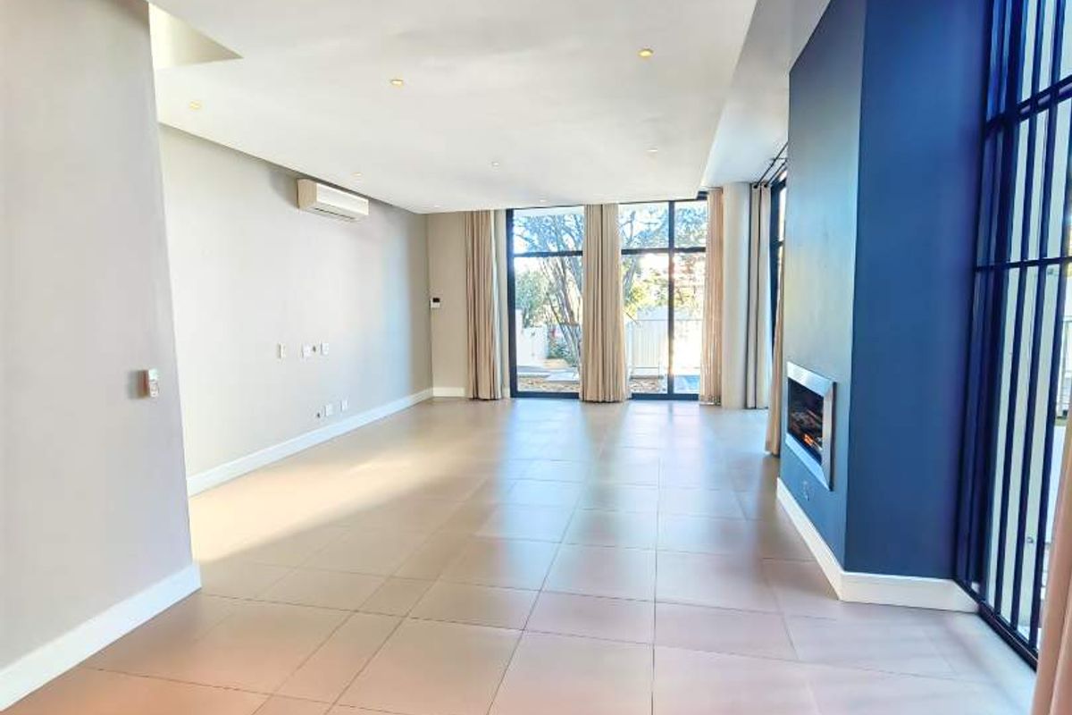 Spacious, light-filled living area featuring large windows, tiled flooring, recessed lighting, a built-in fireplace, and a wall-mounted air conditioning unit.