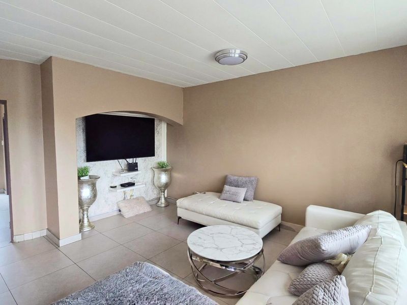 A living room featuring tiled flooring, a neutral color palette, and a built-in arched wall niche for media placement.