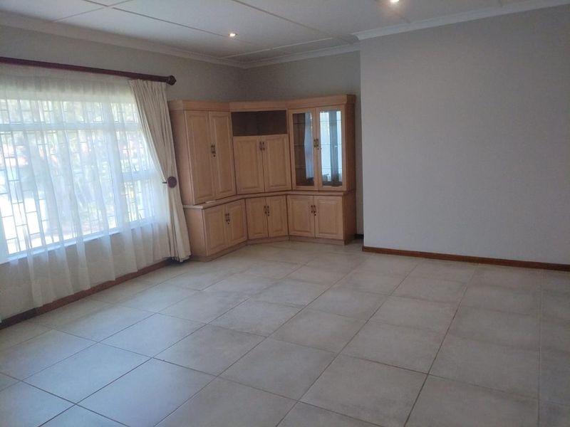 Spacious living area featuring neutral tiled flooring, recessed lighting, and integrated built-in cabinetry, offering a clean and versatile space.