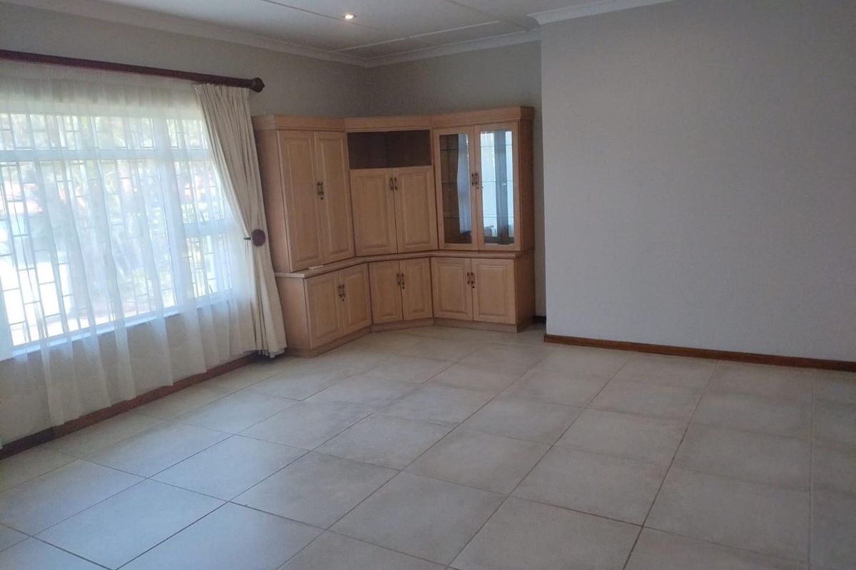 Spacious living area featuring neutral tiled flooring, recessed lighting, and integrated built-in cabinetry, offering a clean and versatile space.