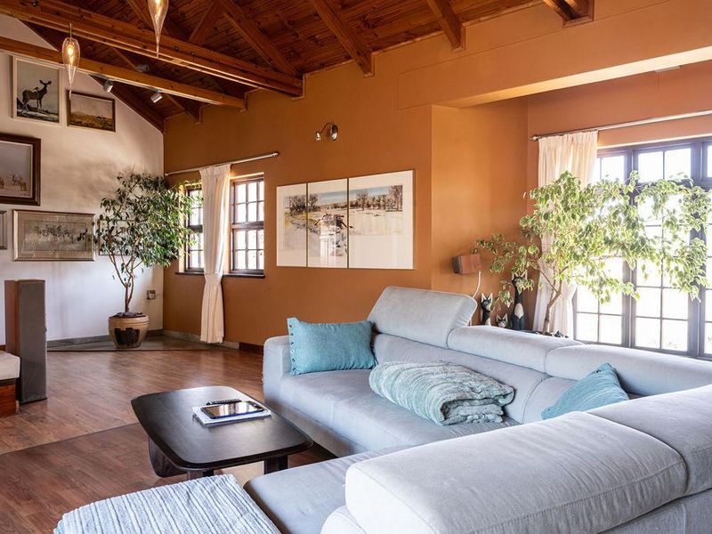 Spacious living room featuring high vaulted timber ceilings, warm-toned walls, and large windows that provide ample natural light.