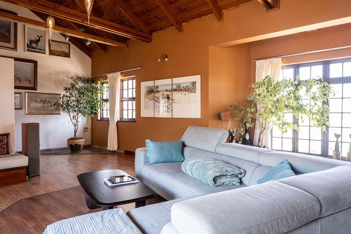 Spacious living room featuring high vaulted timber ceilings, warm-toned walls, and large windows that provide ample natural light.