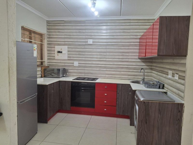 A functional kitchen featuring modern two-tone cabinetry, built-in oven and hob, tiled backsplash, and tiled flooring, providing a practical workspace for daily cooking.