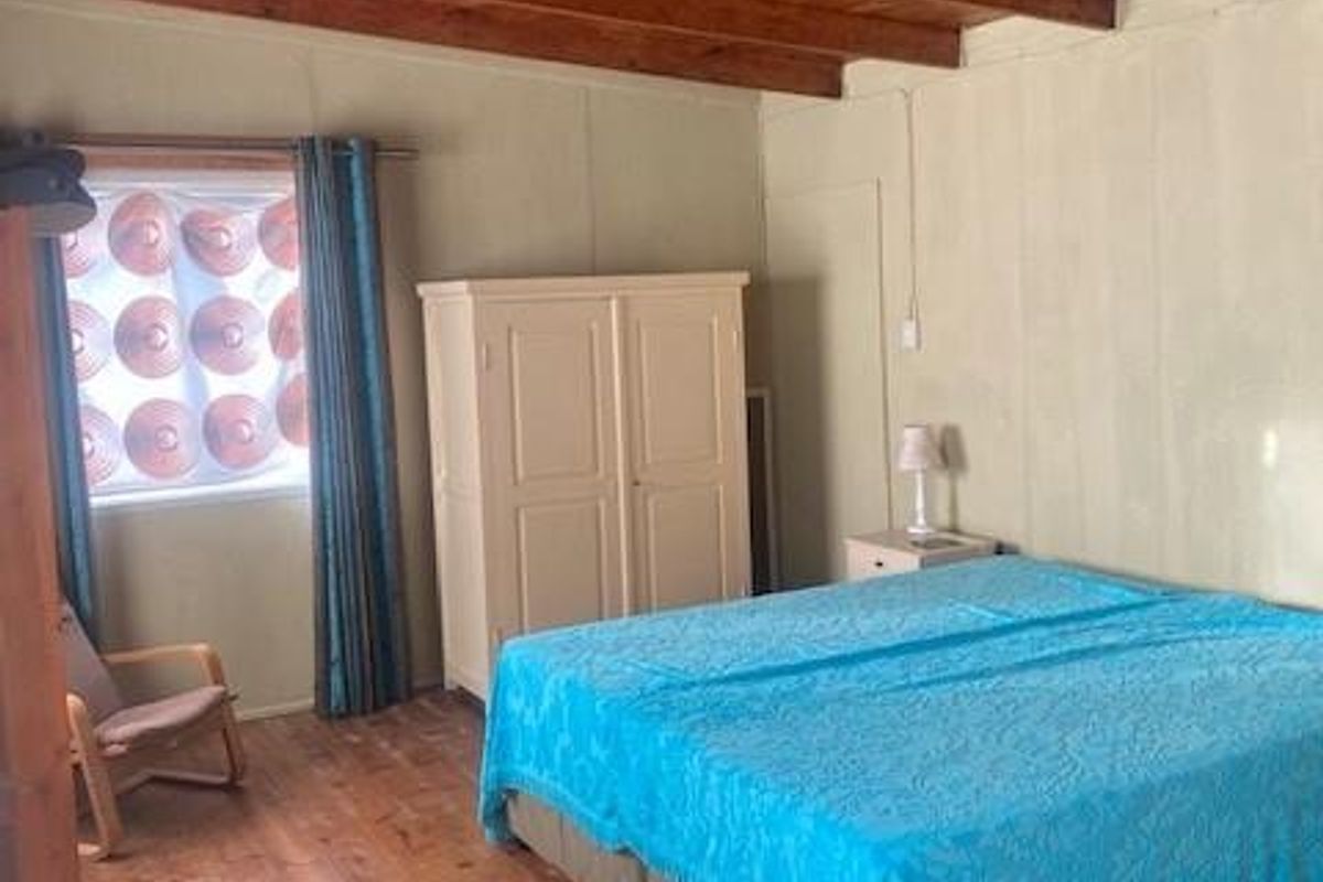 A rustic bedroom featuring exposed timber ceiling beams and natural wood flooring, creating a warm and traditional atmosphere.