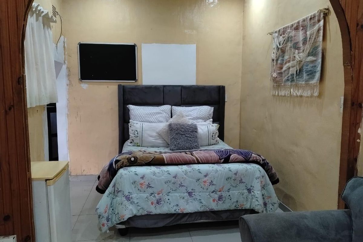 A bedroom featuring tiled flooring and a decorative archway entrance, currently requiring cosmetic updates to the wall finishes.
