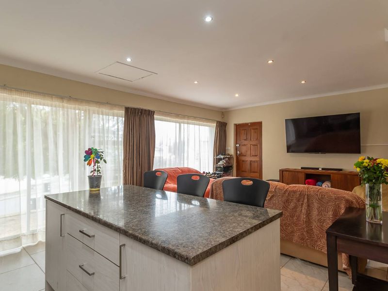 Open-plan living area featuring a central kitchen island with granite countertops, tiled flooring, and recessed lighting, creating a functional and connected space.