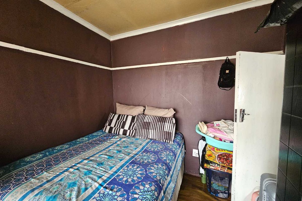 A compact bedroom featuring laminate flooring, coving, and a picture rail. The room requires cosmetic updates including wall and ceiling repairs and repainting.