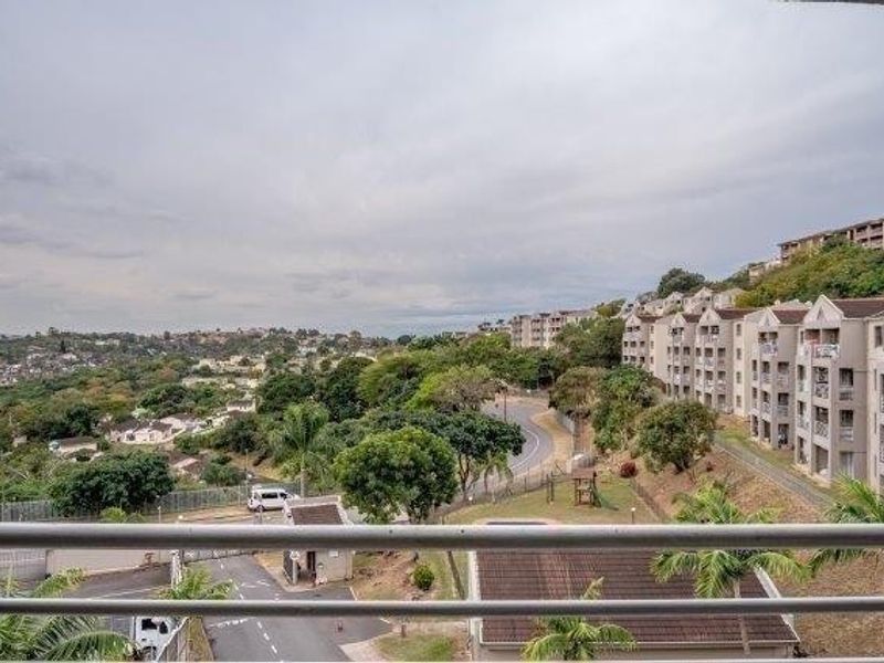 Elevated view overlooking the surrounding residential estate, neighborhood streets, and landscaped grounds from a balcony with a metal railing.