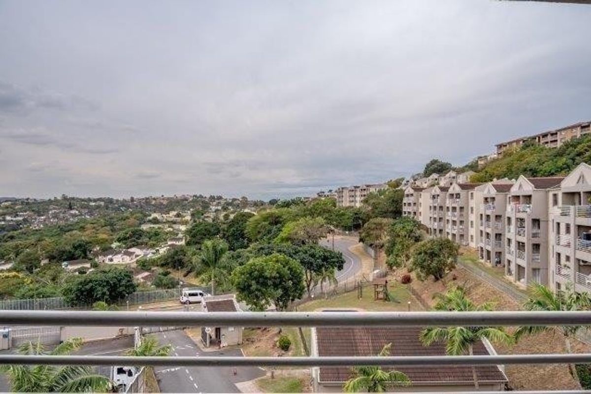 Elevated view overlooking the surrounding residential estate, neighborhood streets, and landscaped grounds from a balcony with a metal railing.