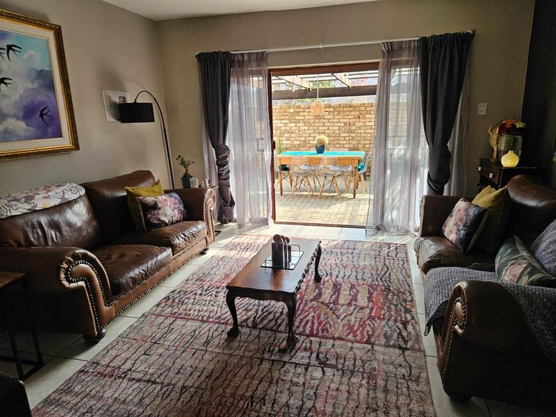 A comfortable living room featuring tiled floors and a large sliding glass door that opens onto a private patio with a timber pergola.