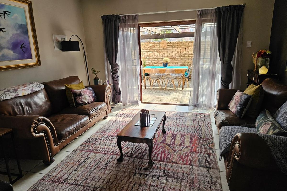 A comfortable living room featuring tiled floors and a large sliding glass door that opens onto a private patio with a timber pergola.