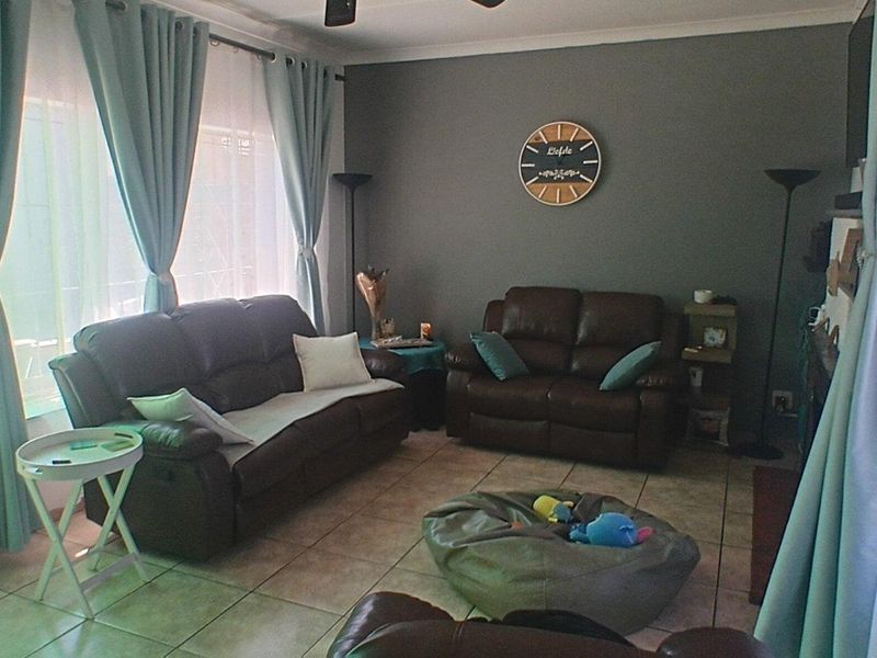 A comfortable living room featuring tiled flooring, a ceiling fan, and a sliding glass door providing access to the exterior.