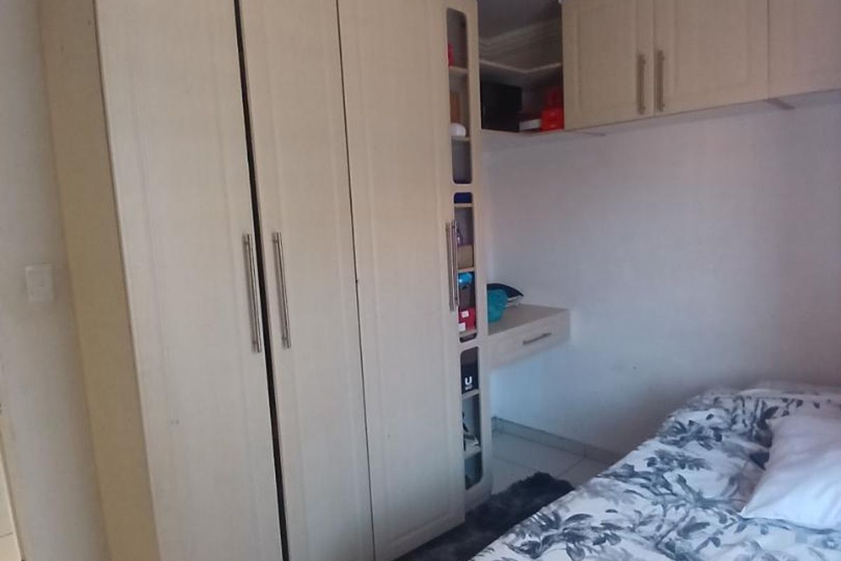 A bedroom featuring built-in floor-to-ceiling cabinetry with integrated shelving and overhead storage units, finished with tiled flooring.