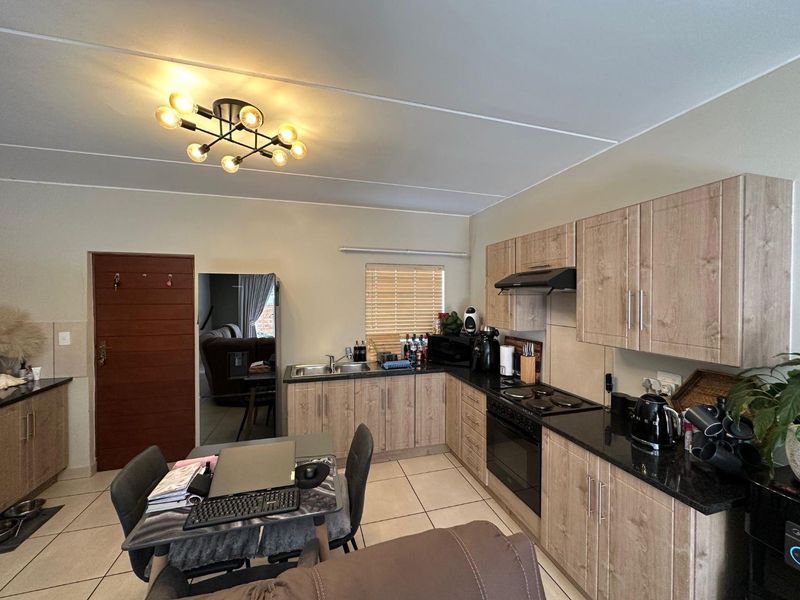 A functional kitchen featuring light wood-look cabinetry, dark granite countertops, built-in oven with hob, and tiled flooring.