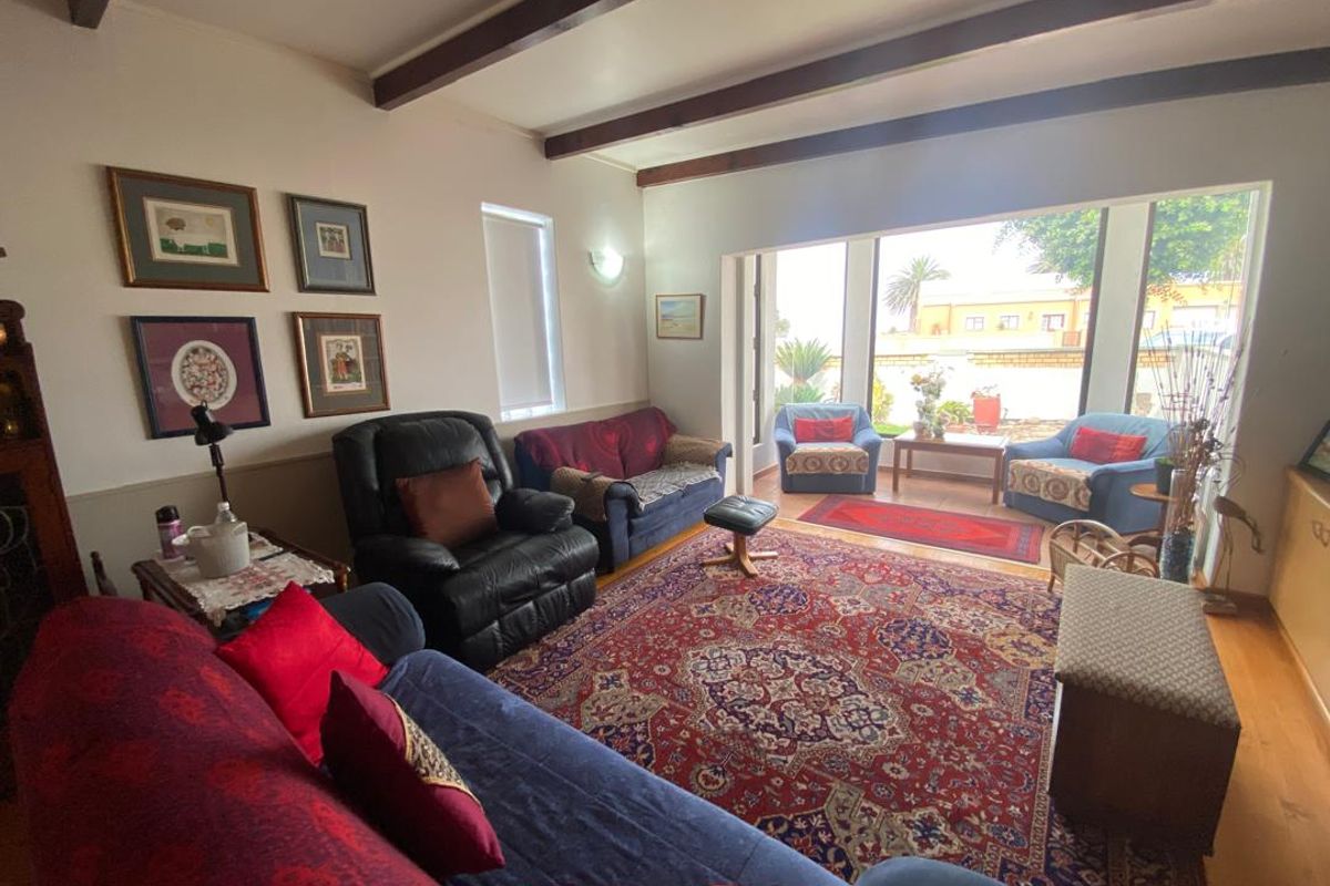 Spacious living room featuring exposed timber ceiling beams, hardwood flooring, and large sliding glass doors providing direct access to the outdoor patio area.