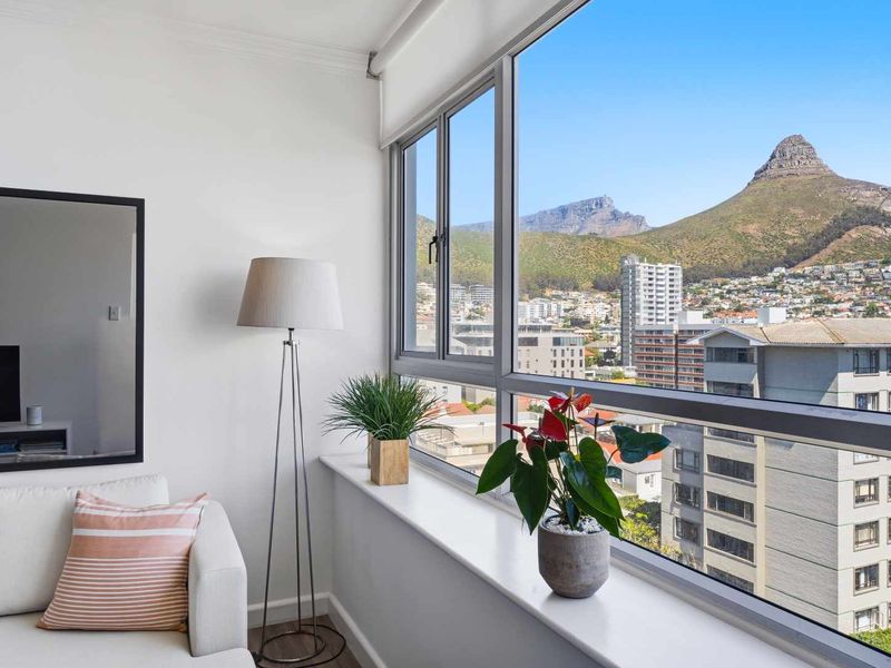 A bright living area featuring a large window with expansive mountain and city views.