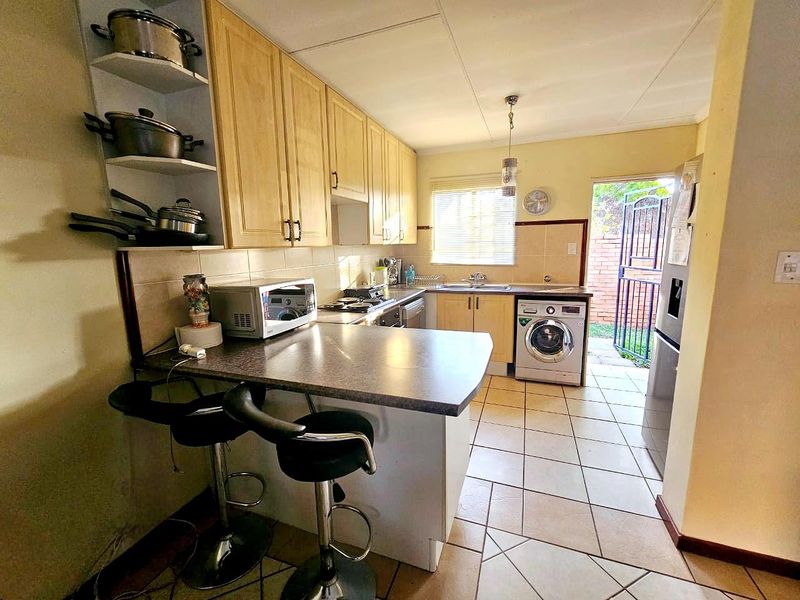 Functional kitchen featuring built-in cabinetry, tiled flooring, and direct access to the rear exterior through a security gate.