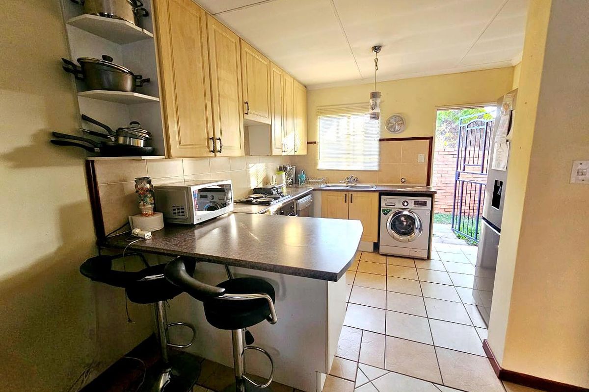 Functional kitchen featuring built-in cabinetry, tiled flooring, and direct access to the rear exterior through a security gate.