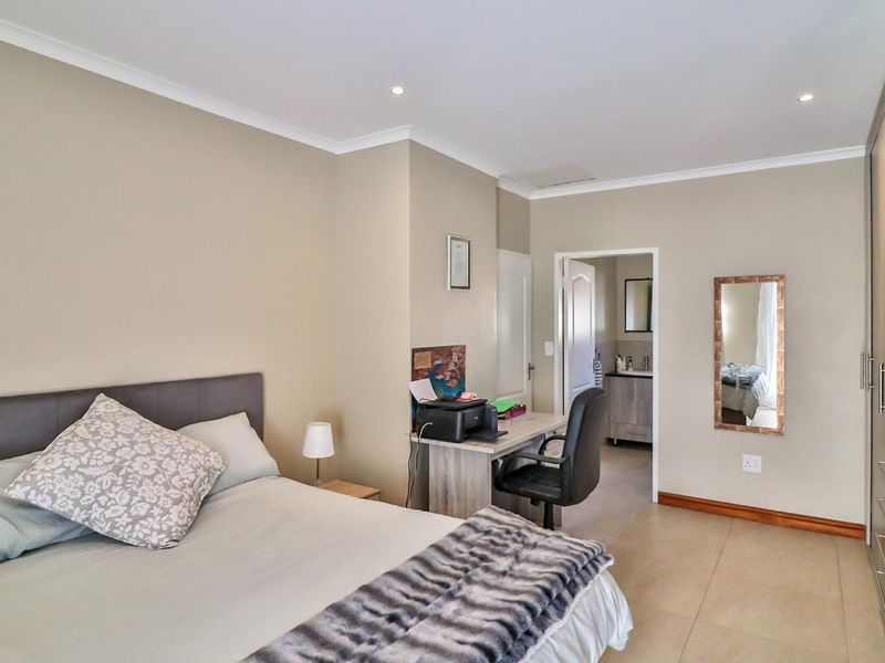 Spacious bedroom featuring neutral walls, tiled flooring, built-in cupboards, recessed lighting, and convenient access to an en-suite bathroom.