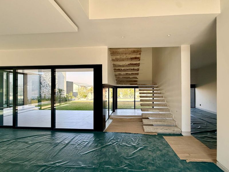 Spacious open-plan living area featuring a modern floating concrete staircase and large sliding glass doors leading to the rear garden.