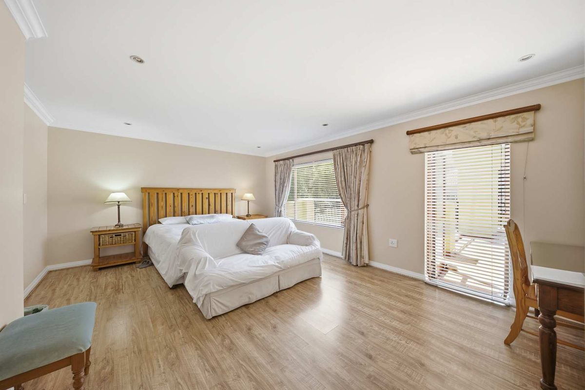 Spacious bedroom featuring light wood-look laminate flooring, recessed lighting, and direct access to an outdoor area through a sliding glass door.