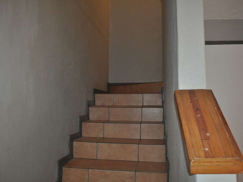 A functional staircase featuring tiled steps and a wooden handrail, providing access between levels within the townhouse.