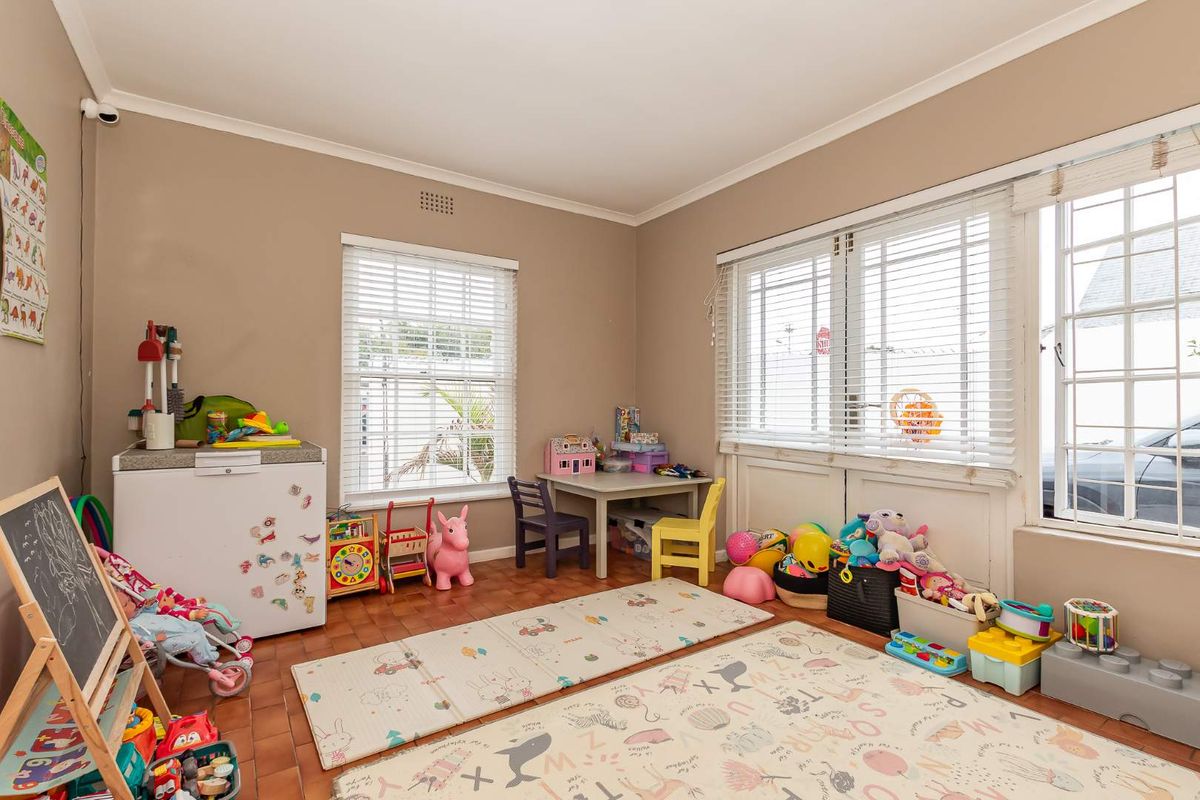 A bright bedroom featuring parquet flooring, large windows with fitted blinds, and coved ceilings, currently utilized as a play area.