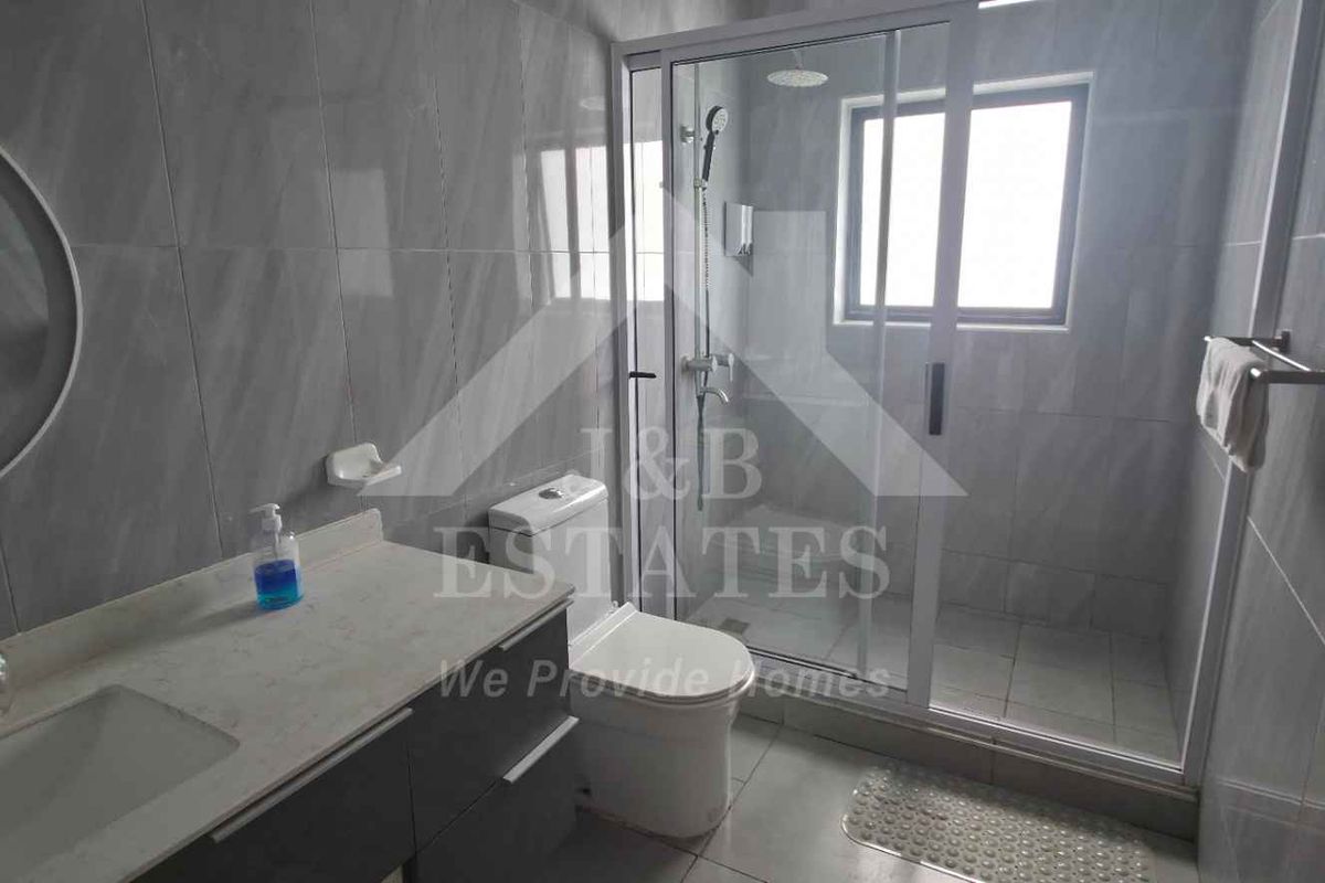 Modern bathroom featuring a vanity with integrated sink, a toilet, and a glass-enclosed shower with tiled finishes throughout.