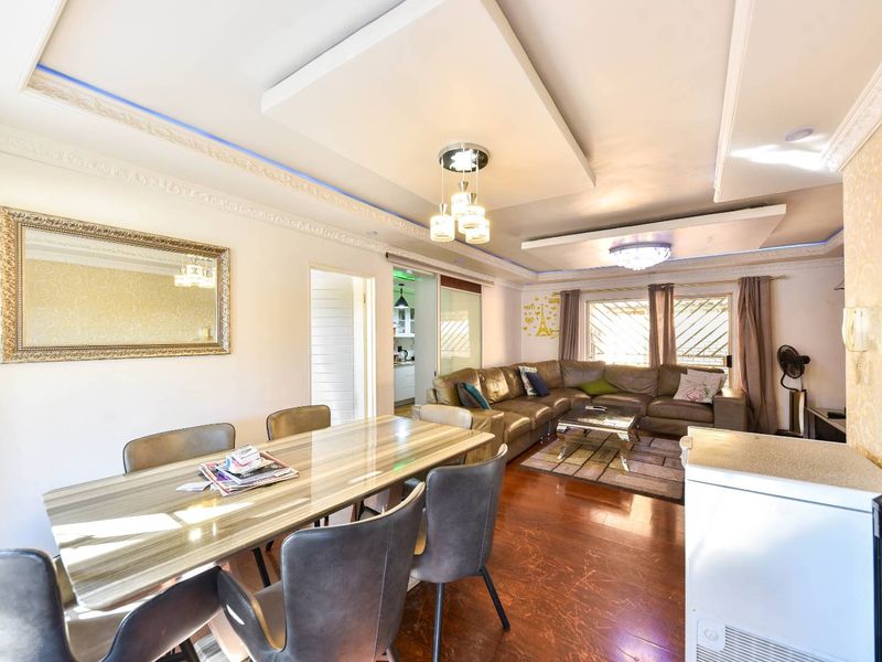 Spacious open-plan living and dining area featuring decorative ceiling details, recessed lighting, and laminate flooring, creating a bright and functional living space.