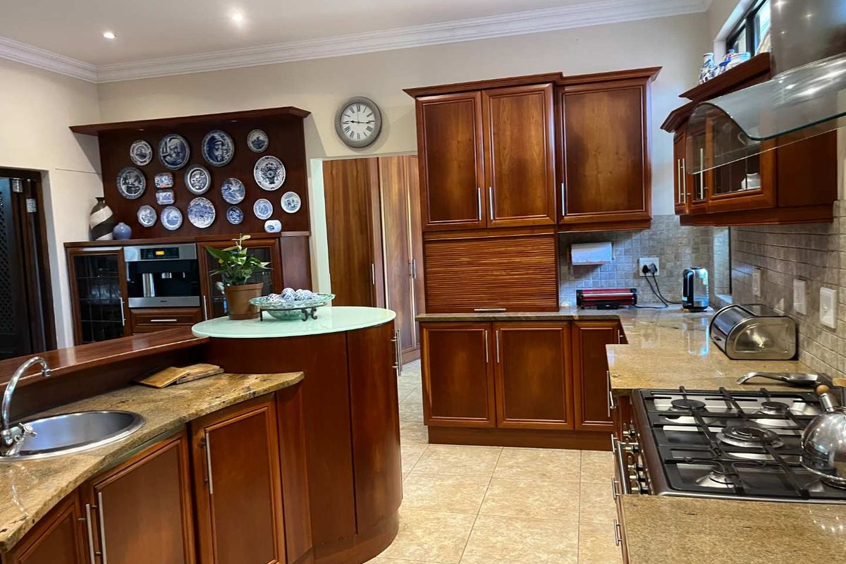 Traditional kitchen featuring rich timber cabinetry, granite countertops, a built-in oven, and a gas hob with an integrated extractor fan.