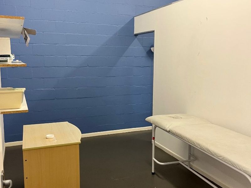 A functional utility or treatment space featuring painted concrete block walls, a partition wall, and durable vinyl flooring.