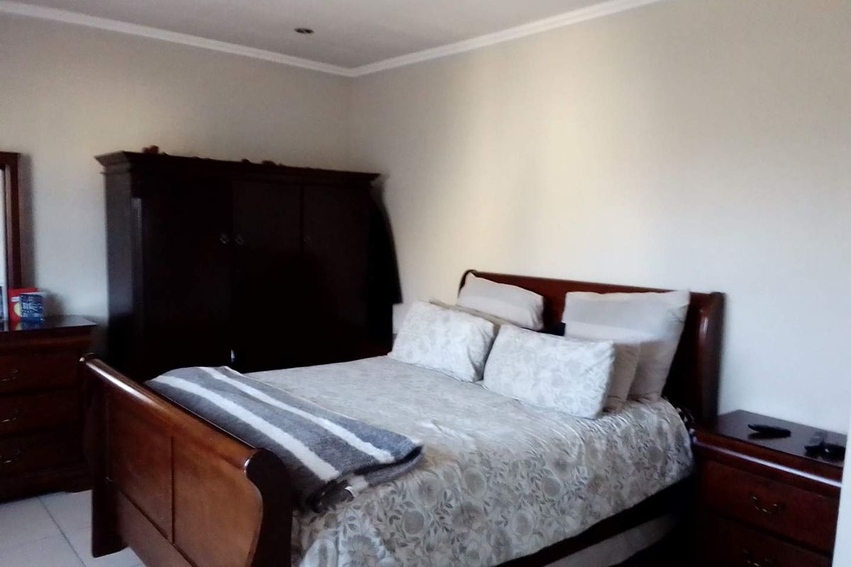 A functional bedroom featuring tiled flooring and recessed downlighting, providing a neutral base for personal styling.